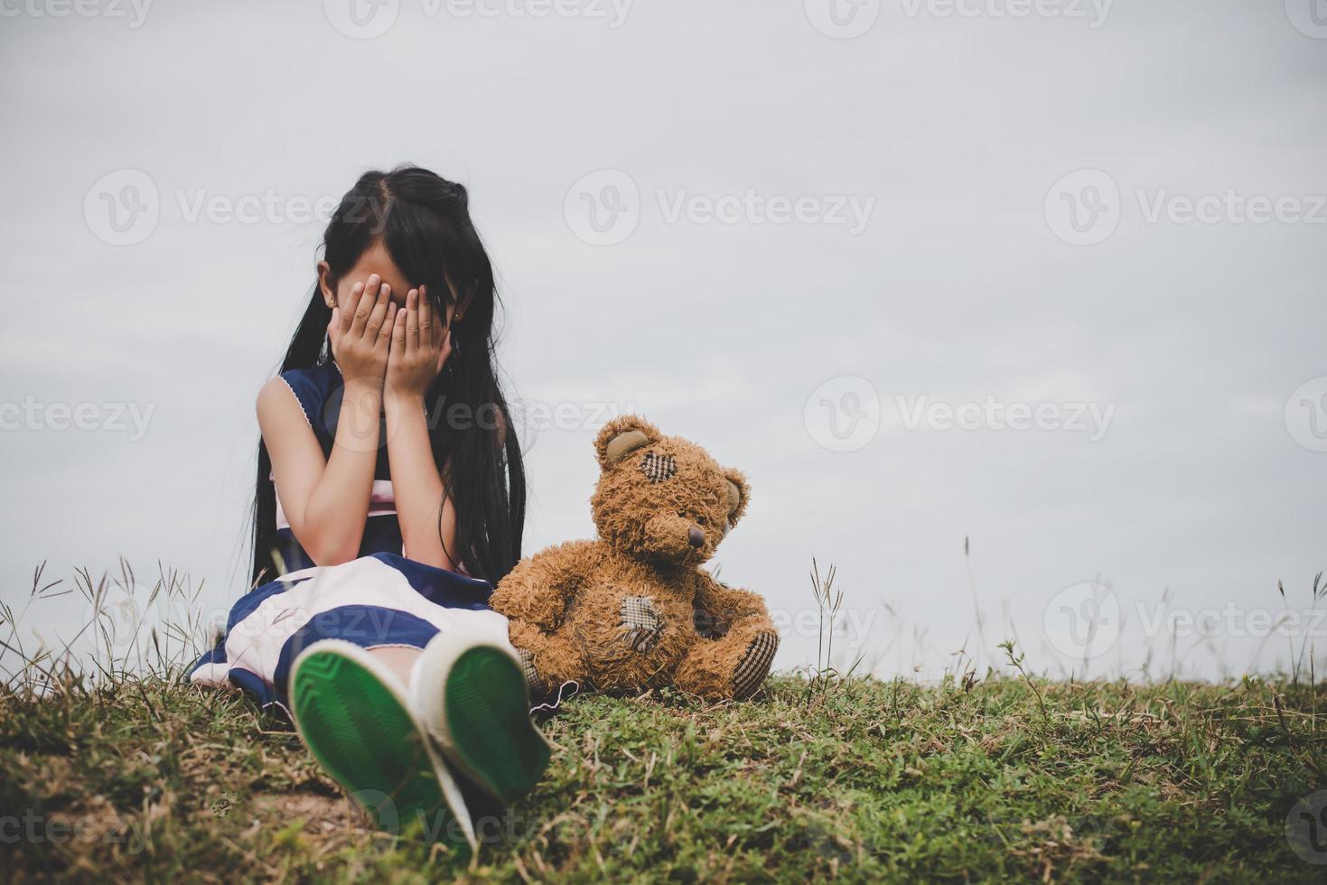 liten flicka som sitter med sin upprörd björn foto