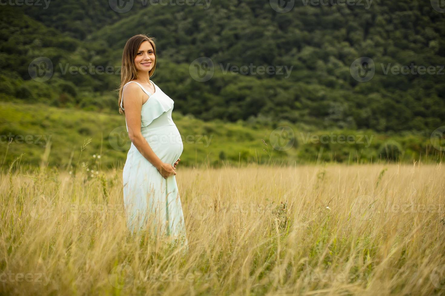 ung gravid kvinna som kopplar av utanför i naturen foto