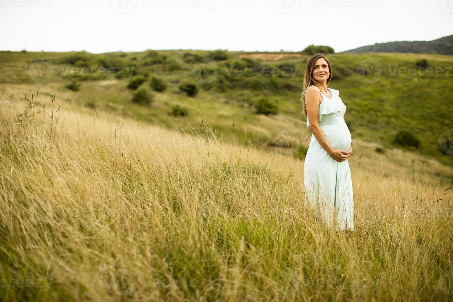 ung gravid kvinna som kopplar av utanför i naturen foto