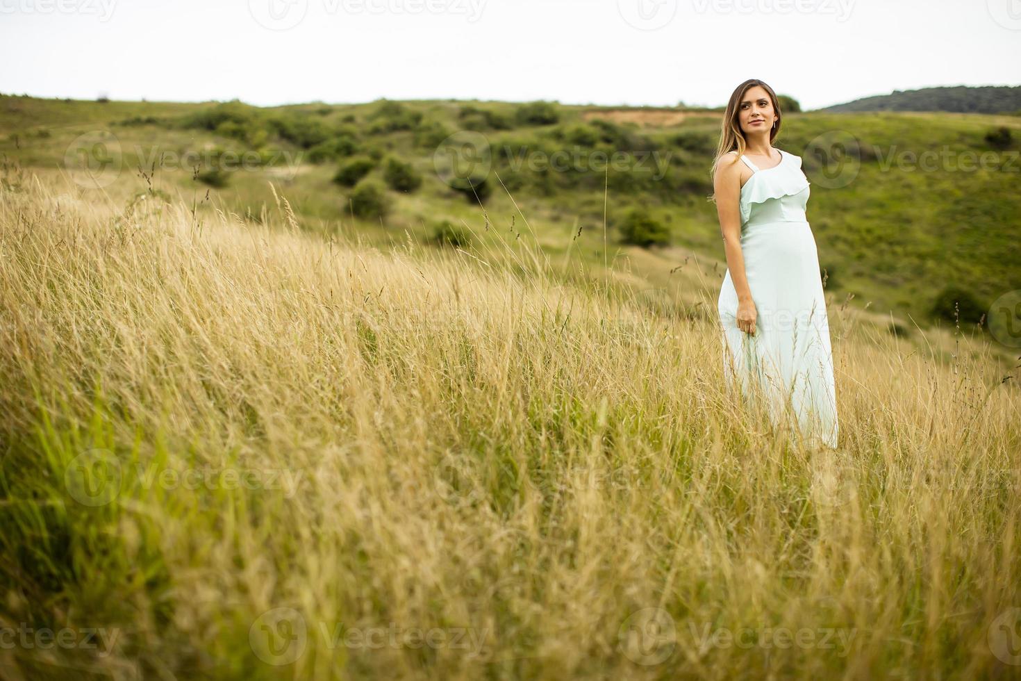 ung gravid kvinna som kopplar av utanför i naturen foto