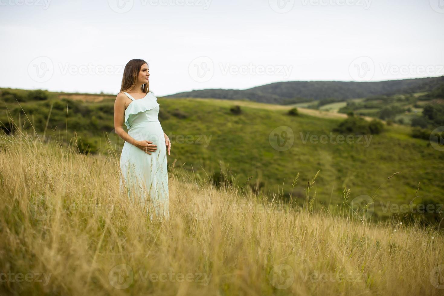 ung gravid kvinna som kopplar av utanför i naturen foto