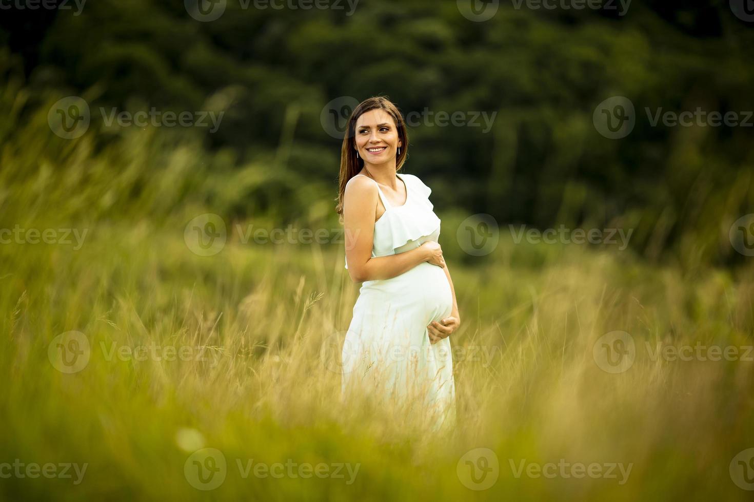 ung gravid kvinna som kopplar av utanför i naturen foto