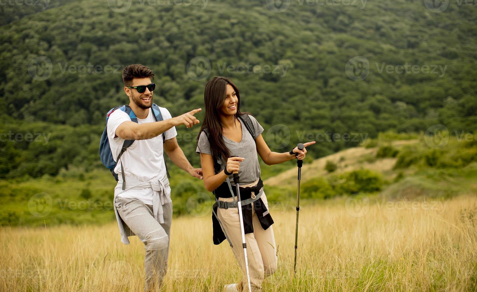 le par som går med ryggsäckar över gröna kullar foto