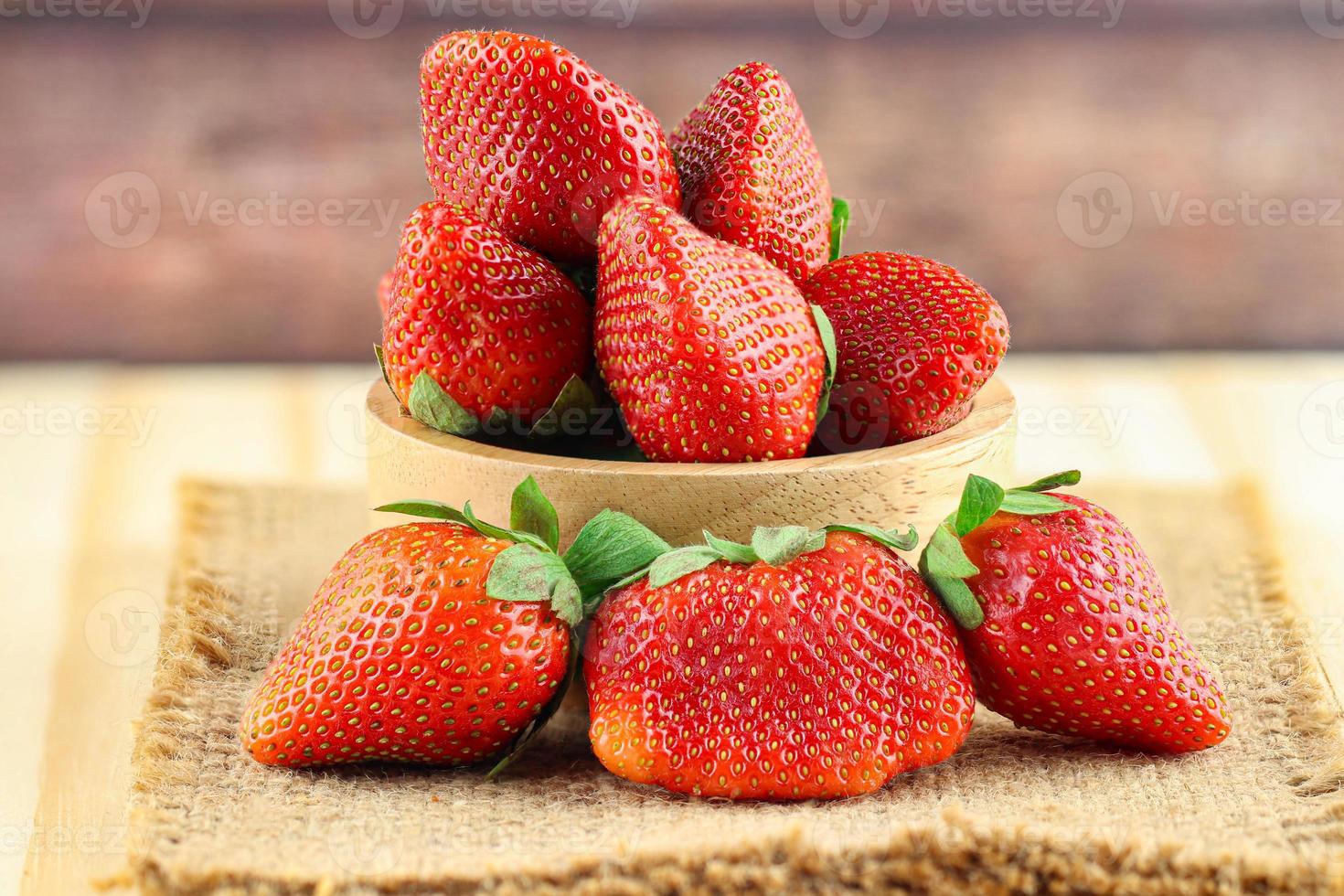 jordgubbar i träskål och säckvävsmatta foto