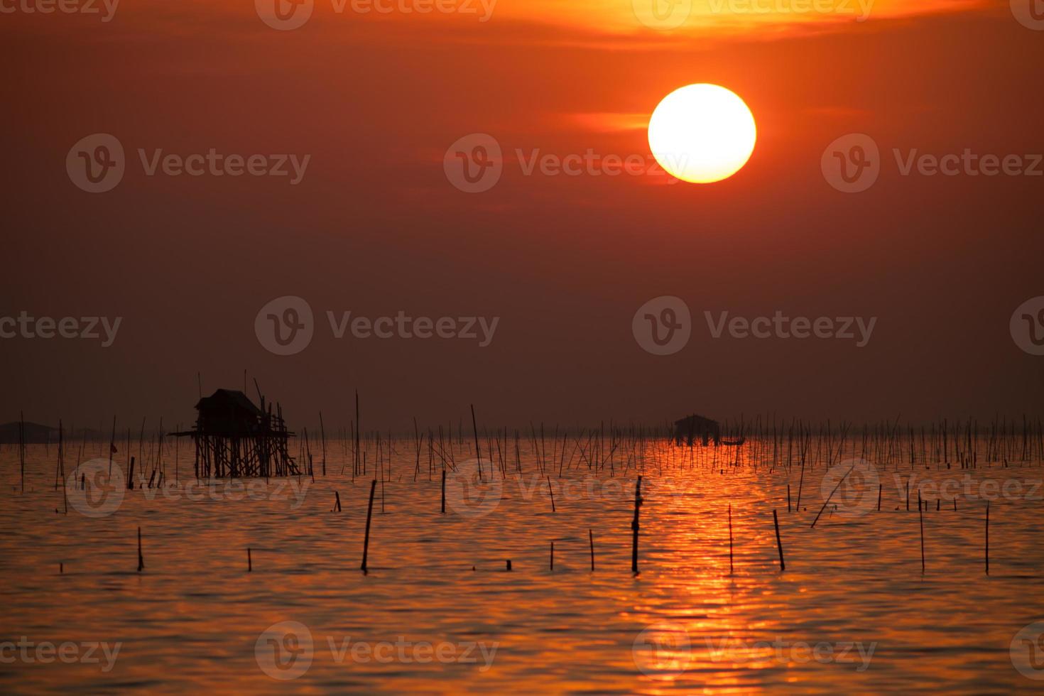 träkoja på vattnet vid solnedgången foto