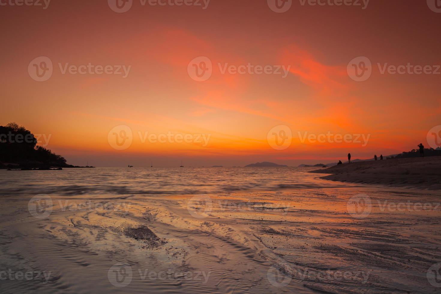 orange solnedgång över vatten på en strand foto