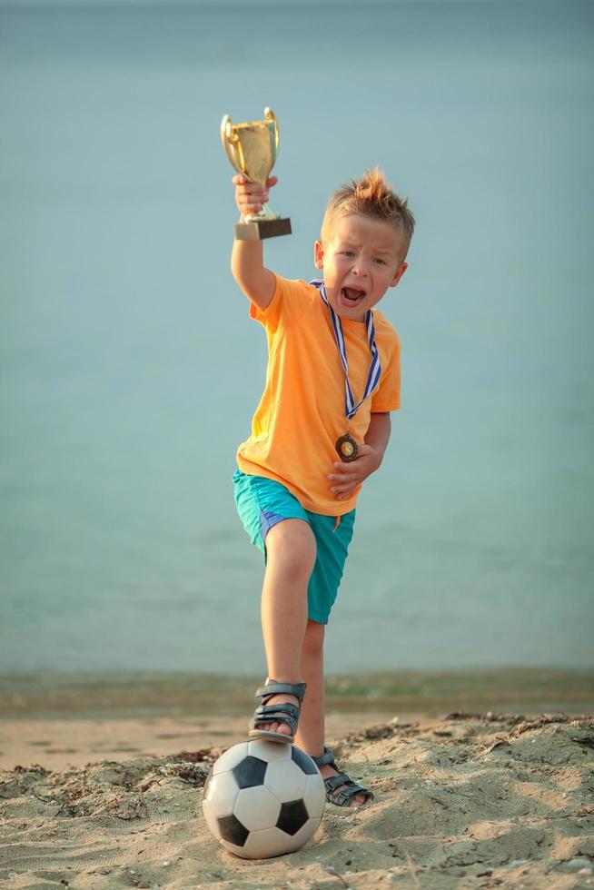 pojke poserar med trofé och fotboll foto