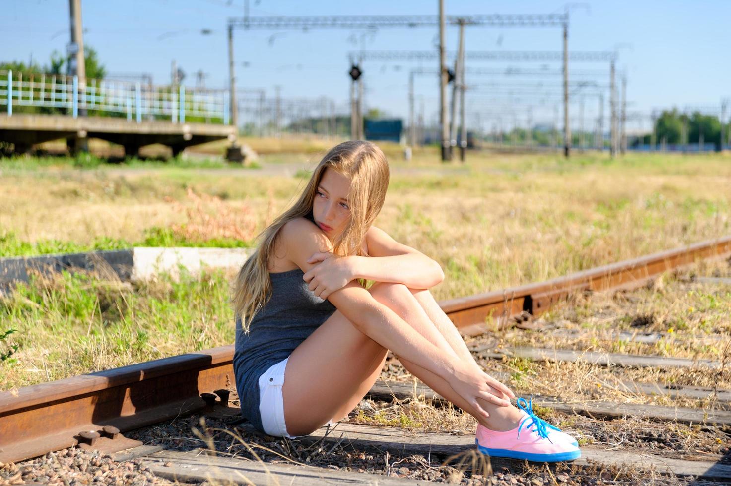 ledsen tjej sitter på ett järnvägsspår foto