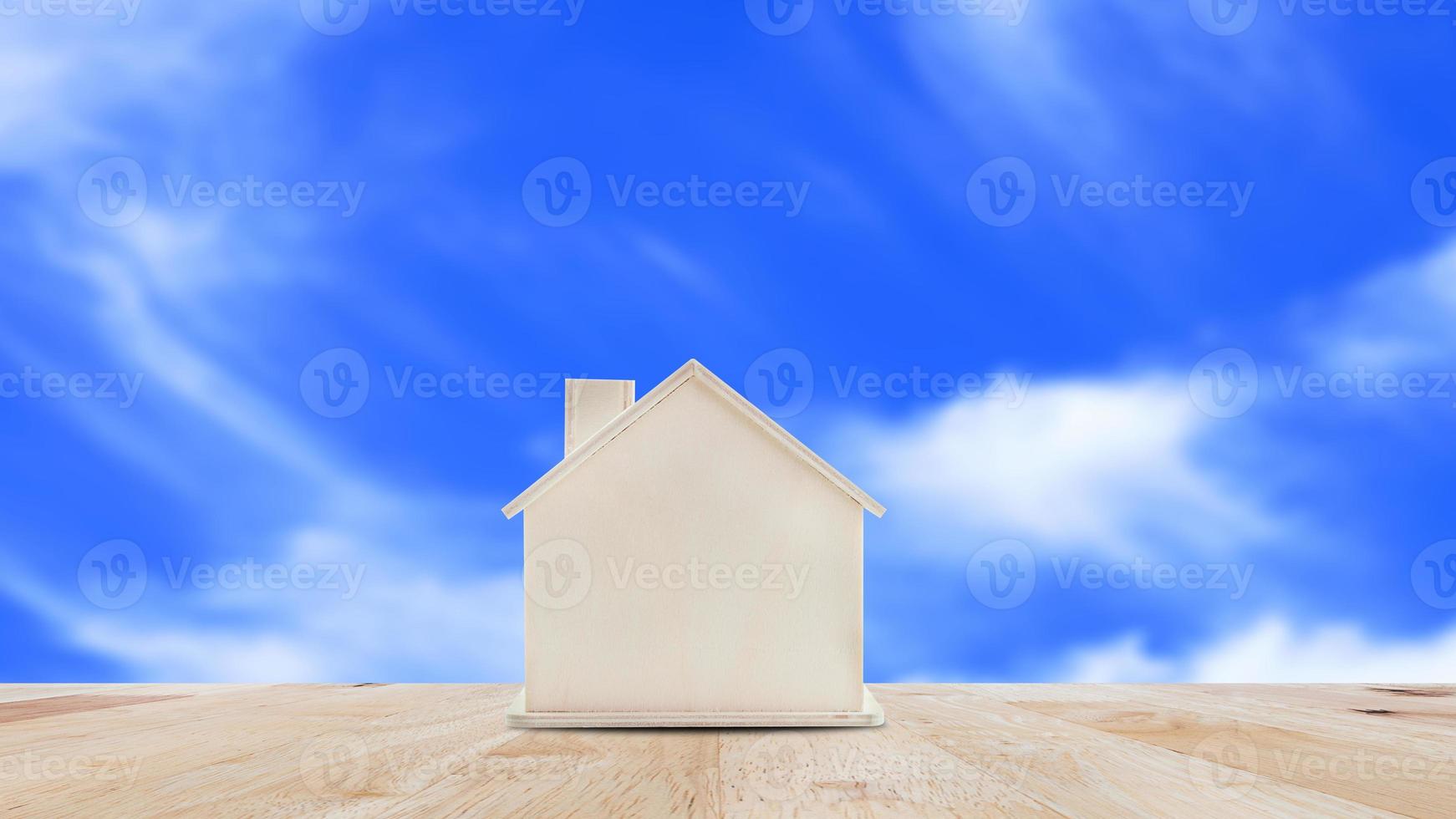 små Hem modell på trä- tabell med blå himmel bakgrund.familj liv och företag verklig egendom begrepp. foto