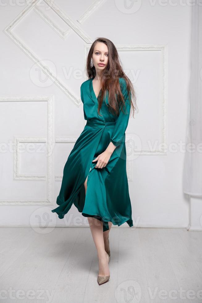 härlig brunett bär i en grön silke klänning foto