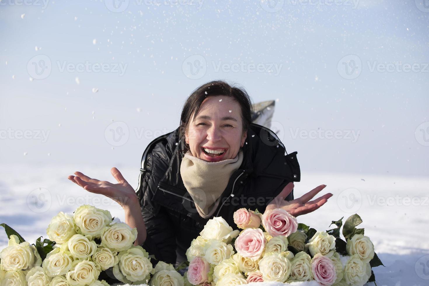 Lycklig äldre kvinna med en bukett av blommor i vinter. foto