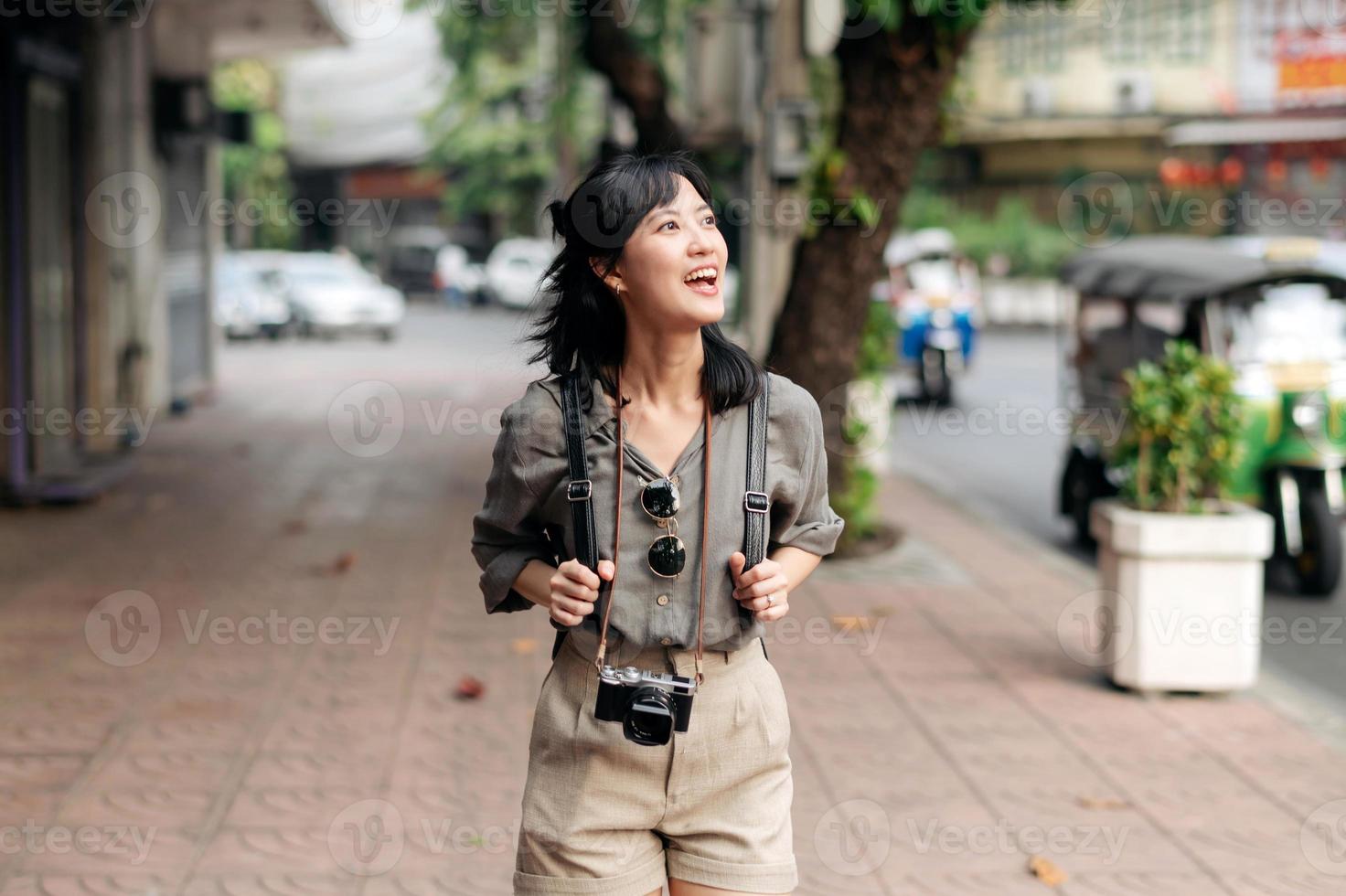 ung asiatisk kvinna ryggsäck resande njuter gata kulturell lokal- plats och leende. resande kontroll ut sida gator. foto