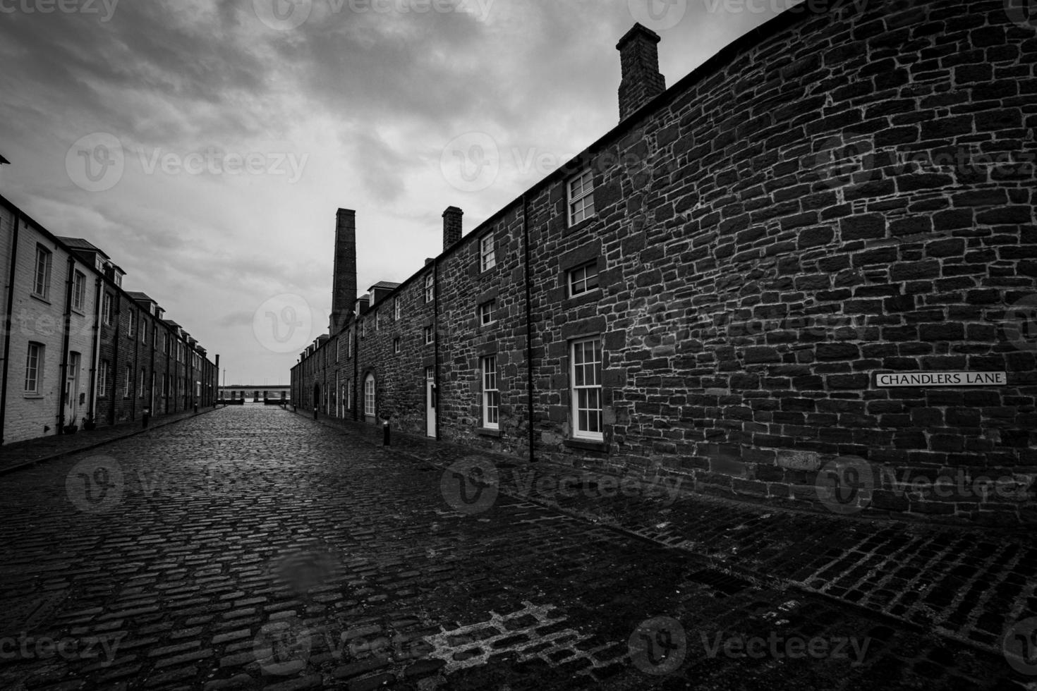 svart och vit gata fotografi kullerstensbelagda väg tegel vägg stormig molnig himmel foto