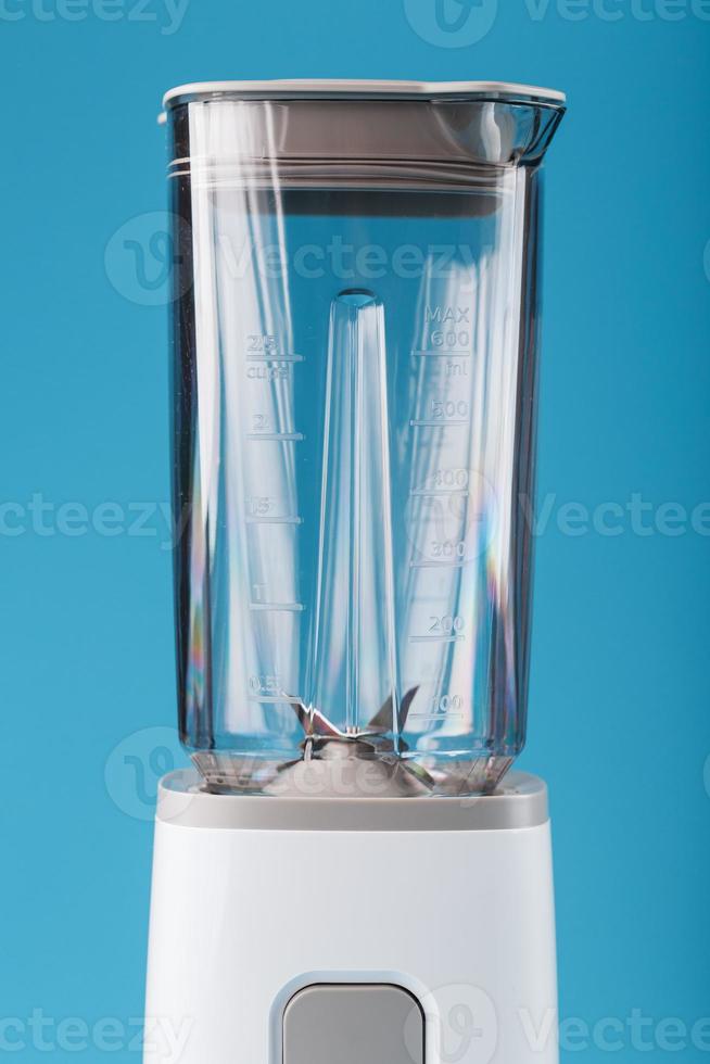 elektrisk blandare med ett tömma kopp på en blå bakgrund. foto