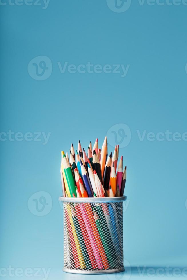 färgrik pennor i en metall burk på en blå bakgrund. foto