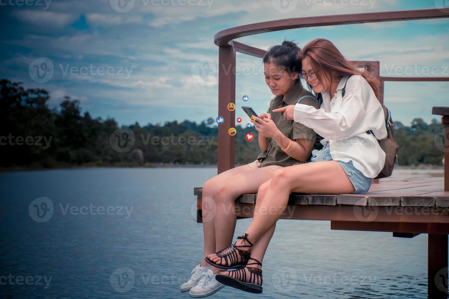 social media och digital uppkopplad begrepp, två glad glad flickor använder sig av smart telefon med social media. de begrepp av levande på semester. två ung Asien kvinnor ryggsäck till resa de högtider. foto