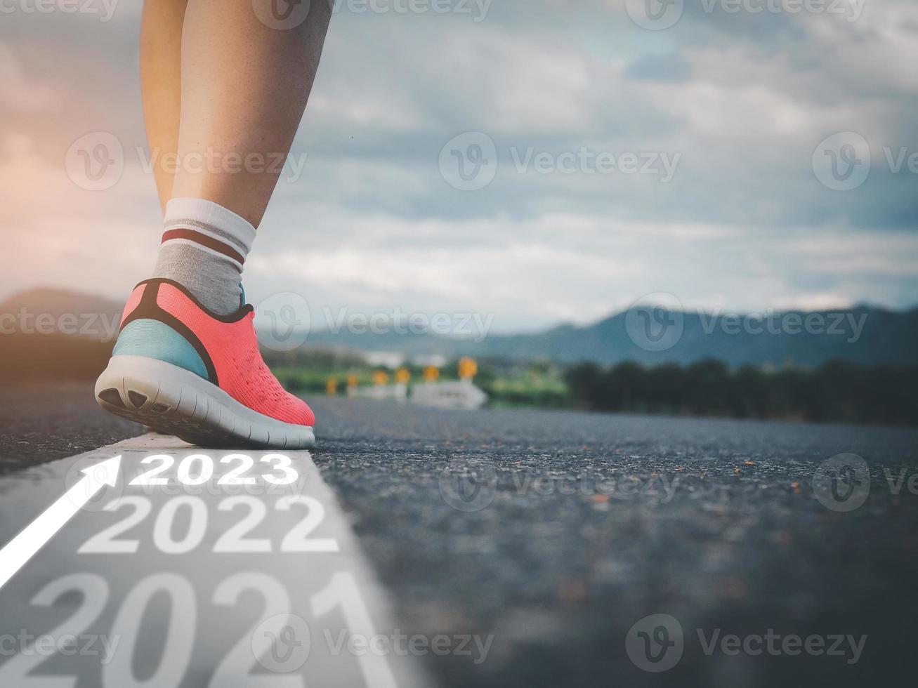 steg in i 2023, kvinna idrottare gående på vit linje på väg med text gående genom varje år och framställning till stiga på de ny år foto