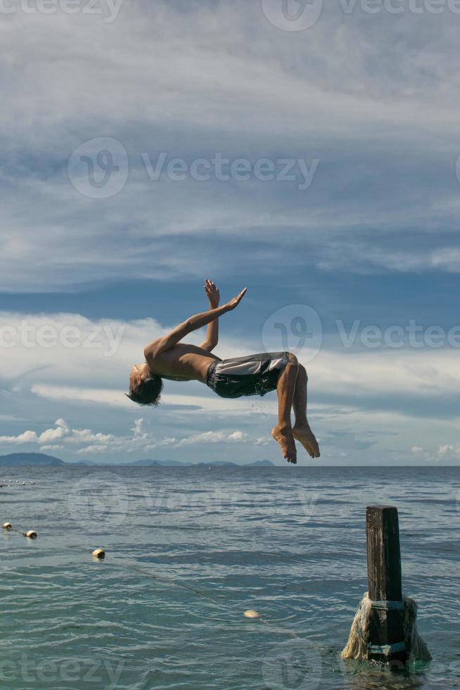 en ung pojke dykning in i de kristall vatten av kapalai malaysia foto