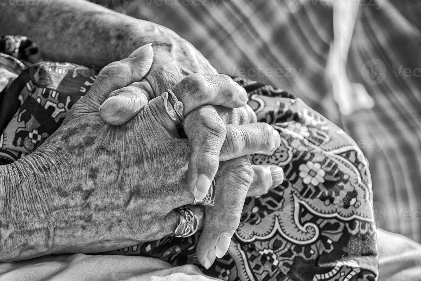 gammal pensionerad kvinna korsade händer i svart och vit foto