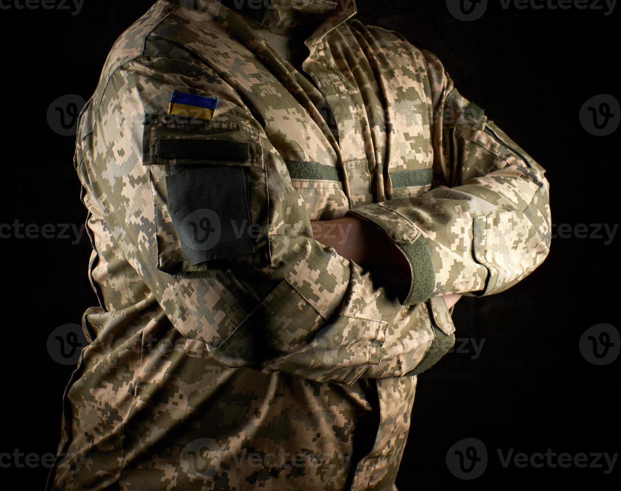 ukrainska soldat i kamouflage enhetlig står med vapen korsade på hans bröst foto