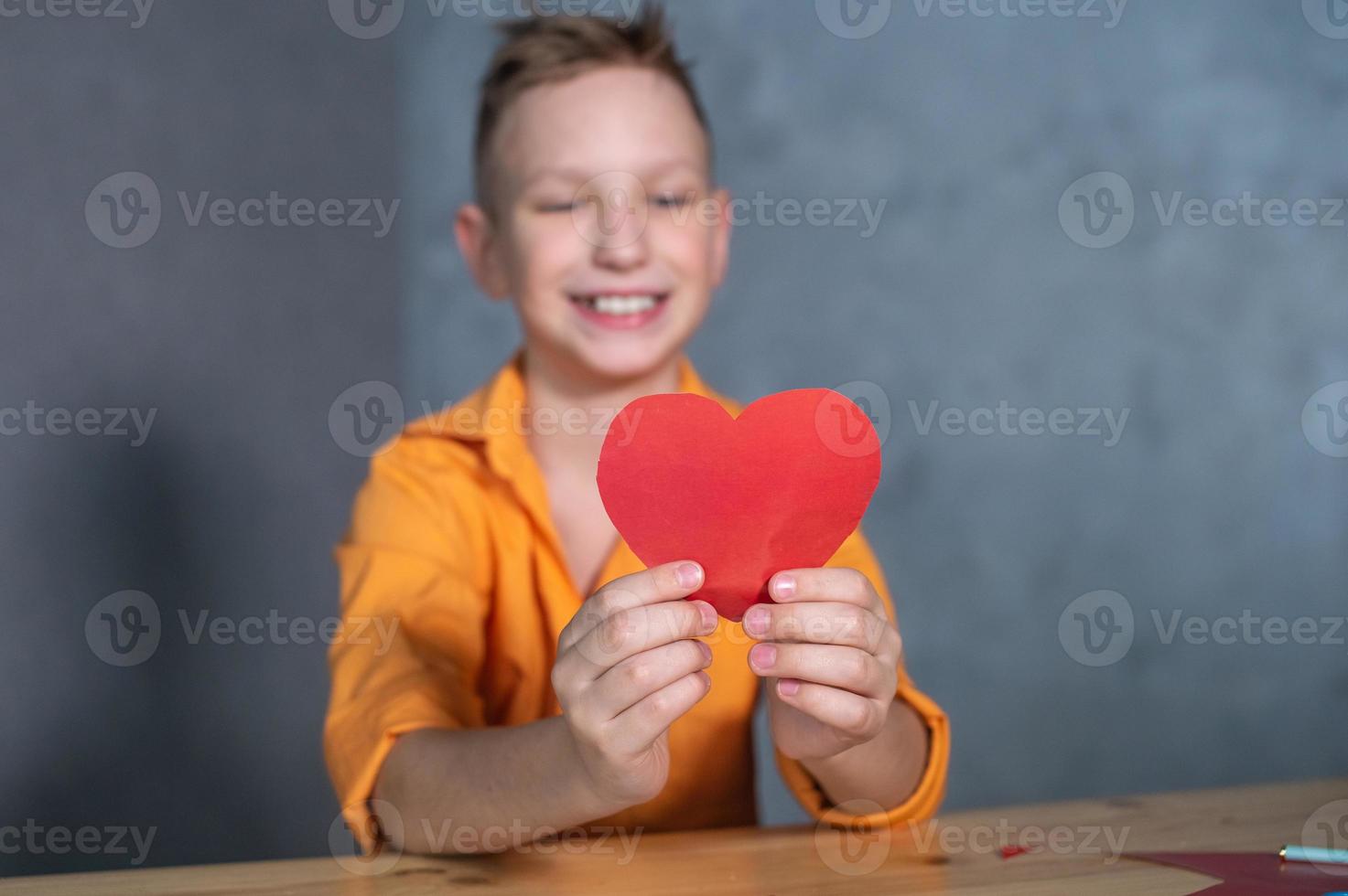 söt pojke gör en hjärtans dag kort med hjärtan foto