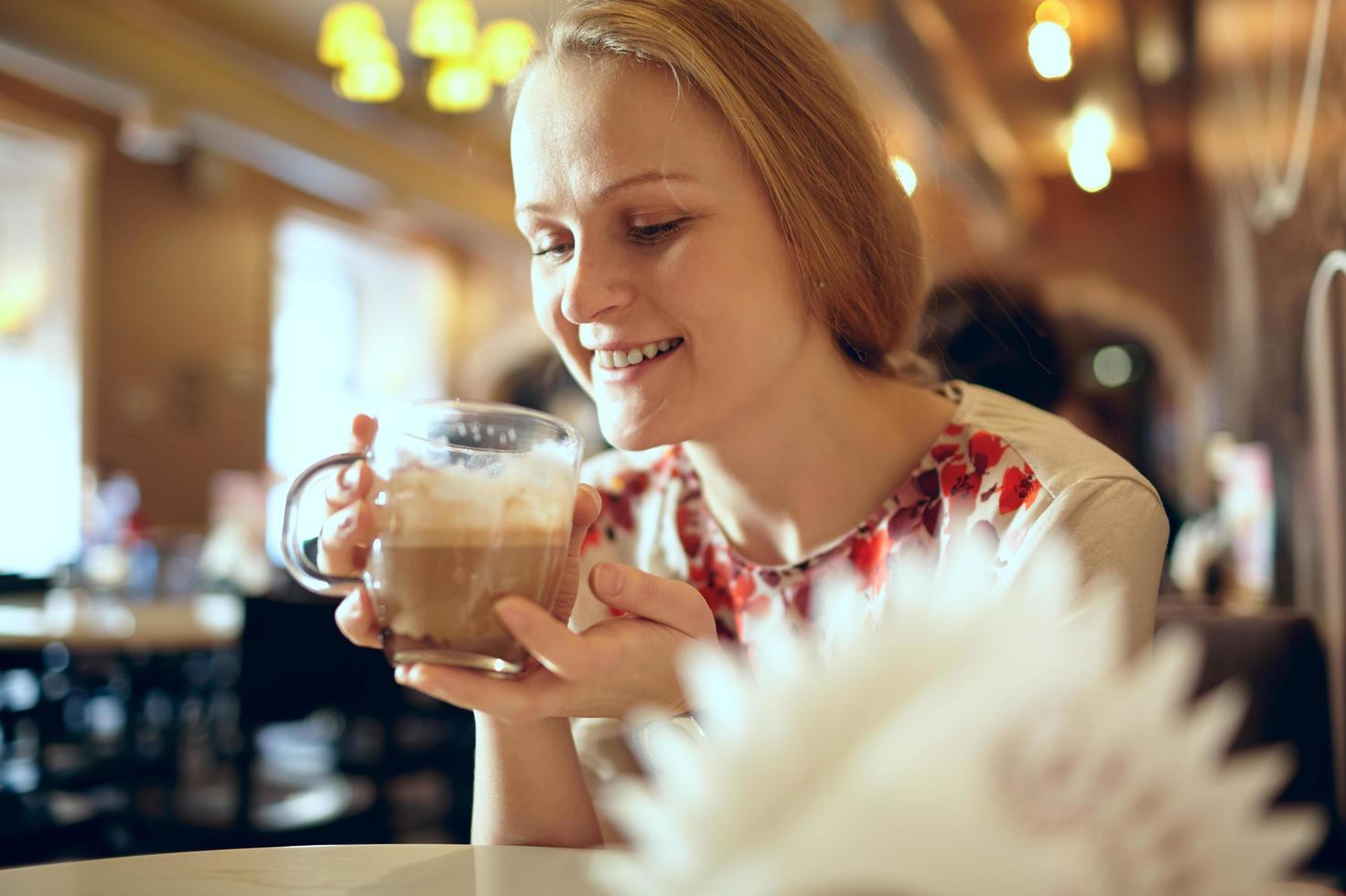 kvinna som dricker en latte på ett kafé foto