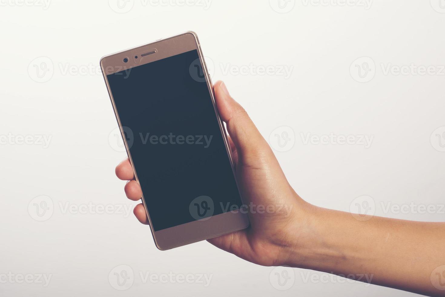 närbild av en kvinna som håller på mobiltelefonen isolerad på vit bakgrund foto