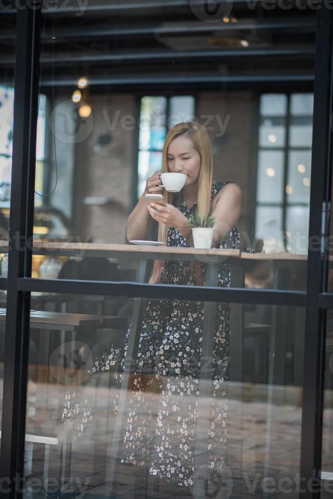 vacker kvinna på ett kafé som dricker kaffe foto