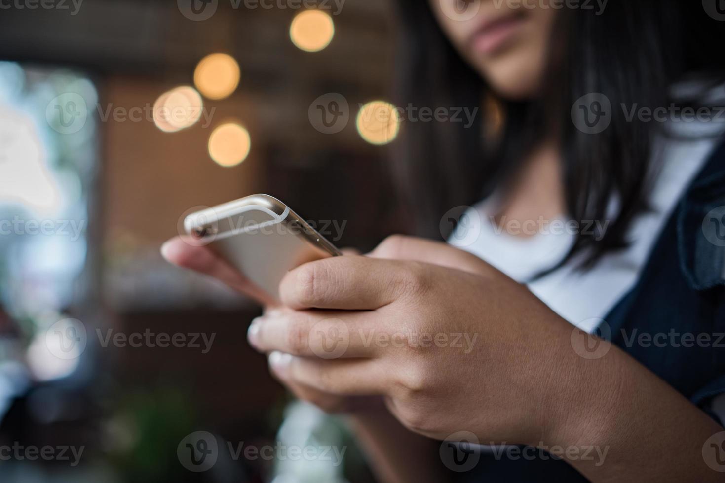 unga kvinnor som använder och tittar på smarttelefonen på fönsterkaféet foto