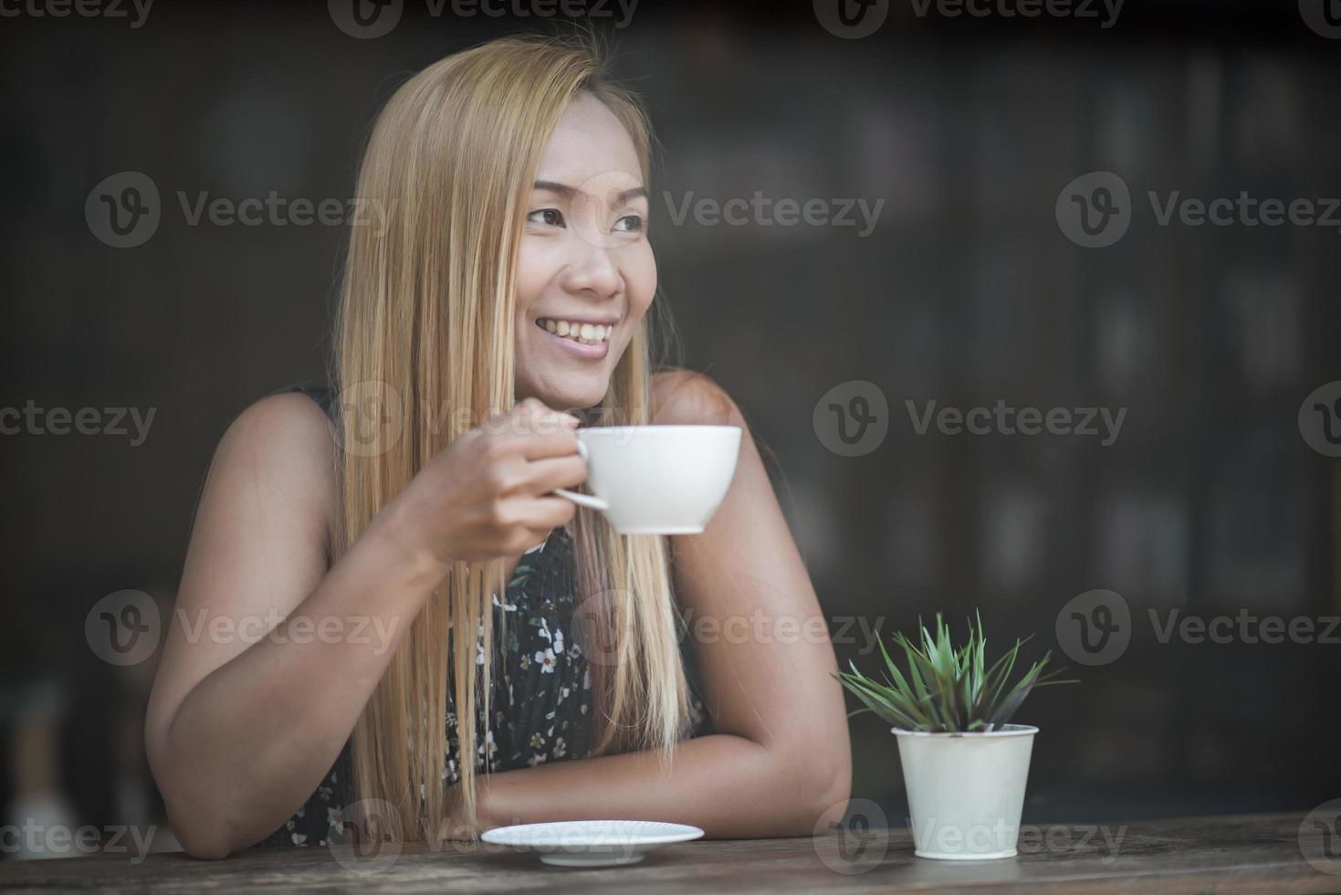 vacker kvinna på ett kafé som dricker kaffe foto