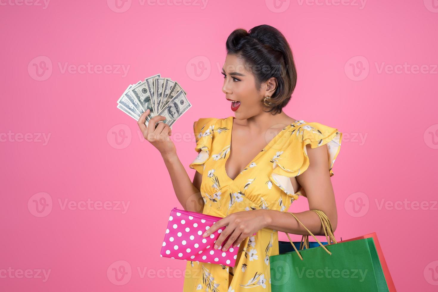 ung moderiktig kvinna som håller en plånbok med kontanter och påsar foto