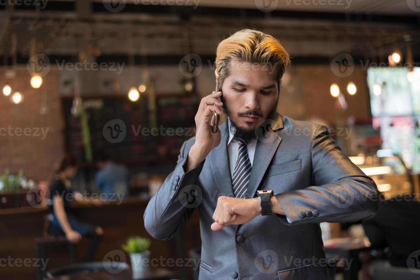 affärsman som talar i telefon och tittar på handklockan foto