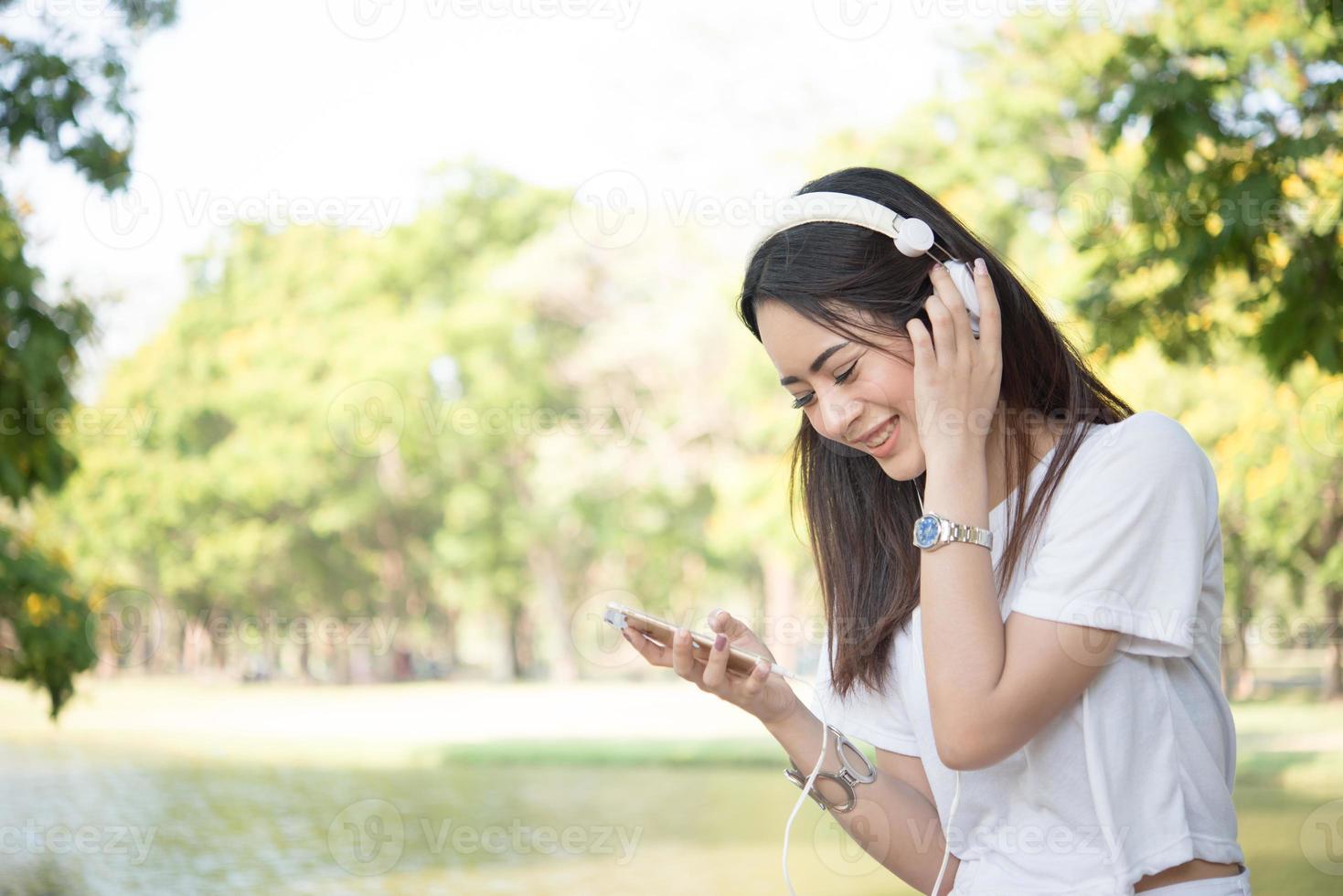 porträtt av en leende flicka med hörlurar som lyssnar på musik i naturen foto