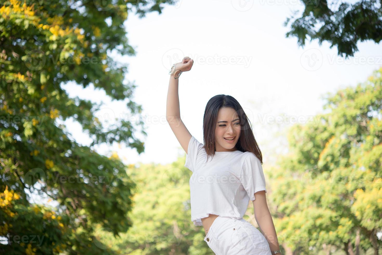 porträtt av en tonårsflicka som lyfter armar och skrattar i parken foto
