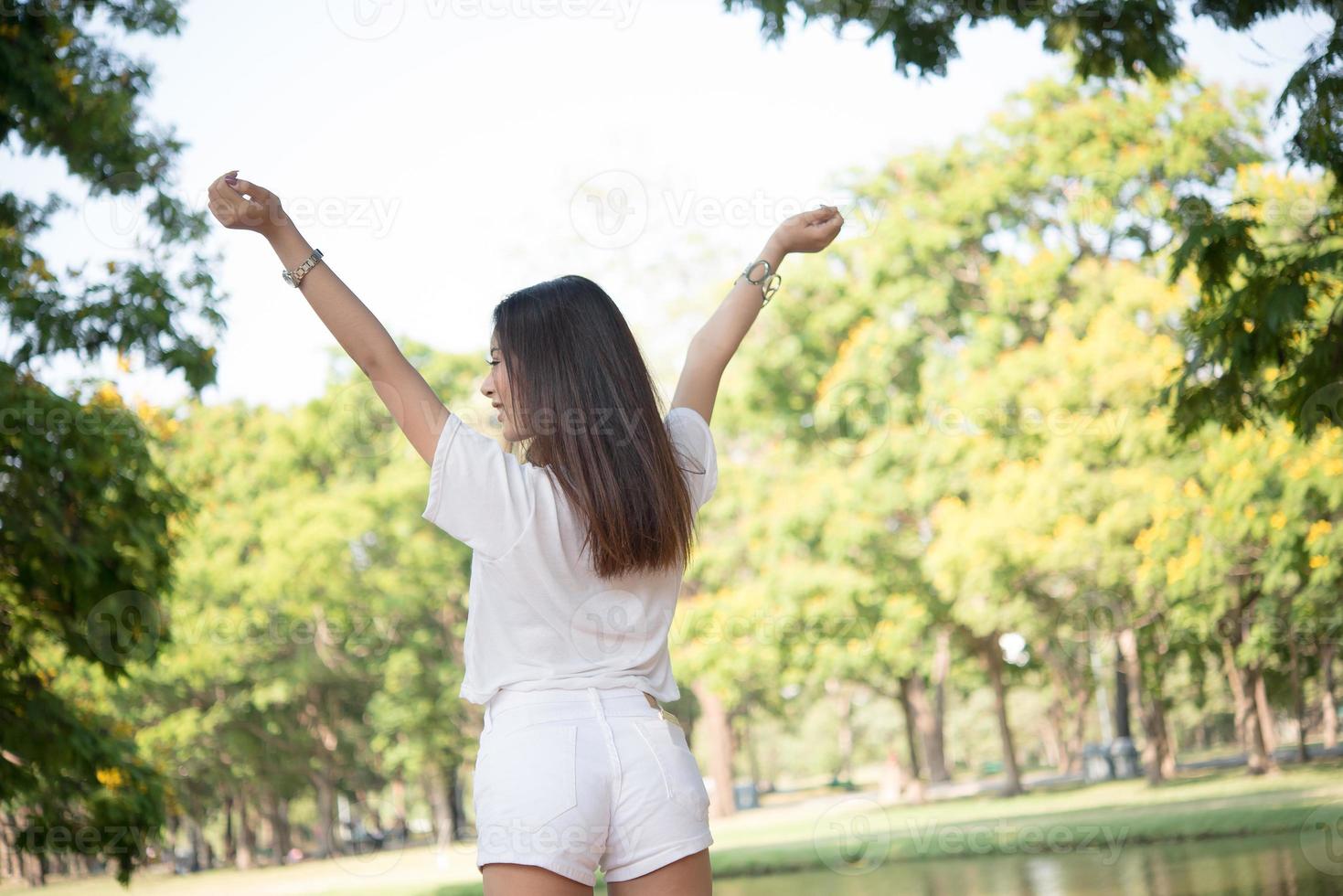 porträtt av en tonårsflicka som lyfter armar och skrattar i parken foto