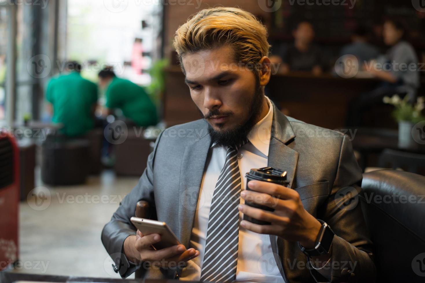 affärsman som sitter på kafé med mobiltelefon foto