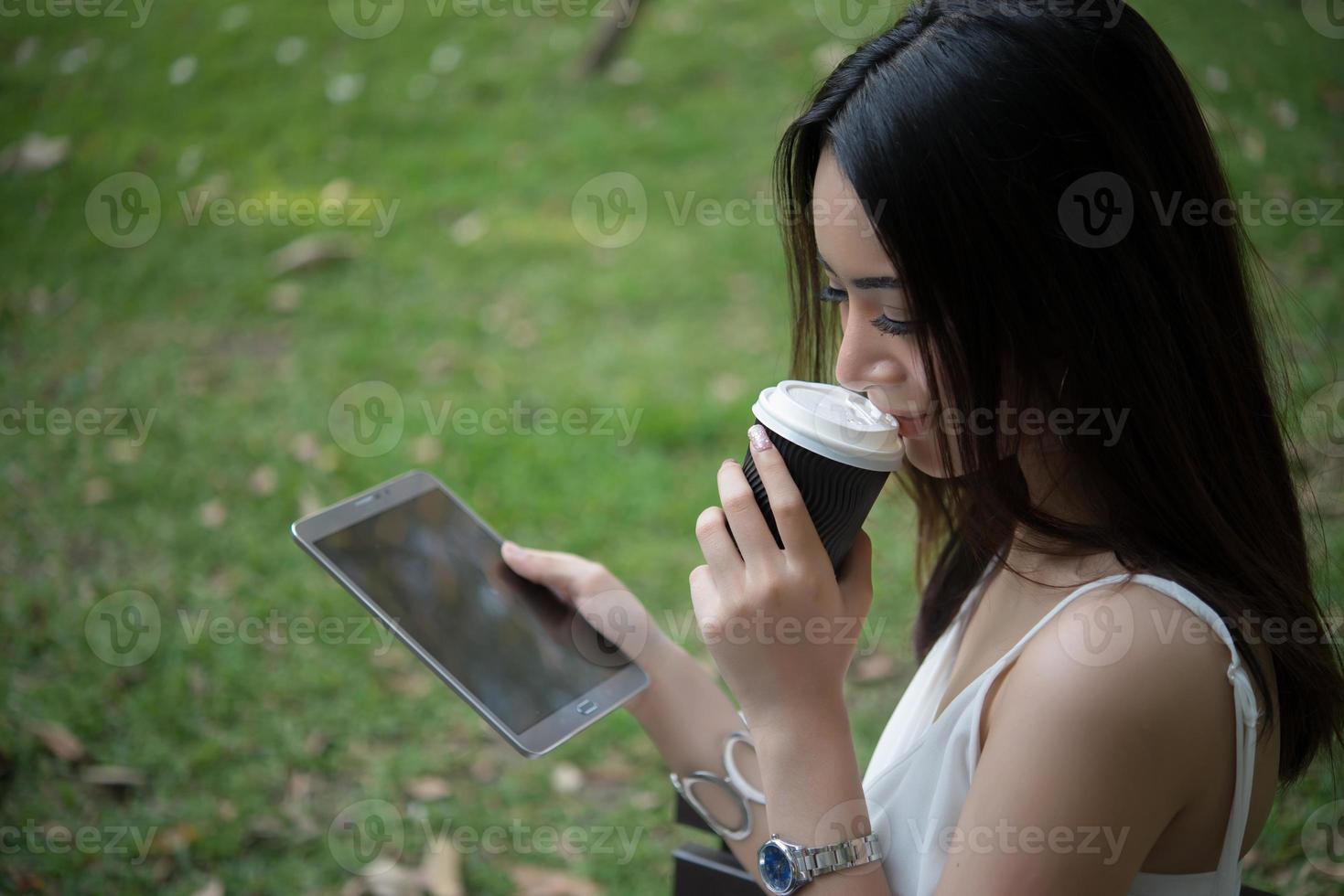 ung vacker kvinna med disponibel kaffekopp och smartphone utomhus foto