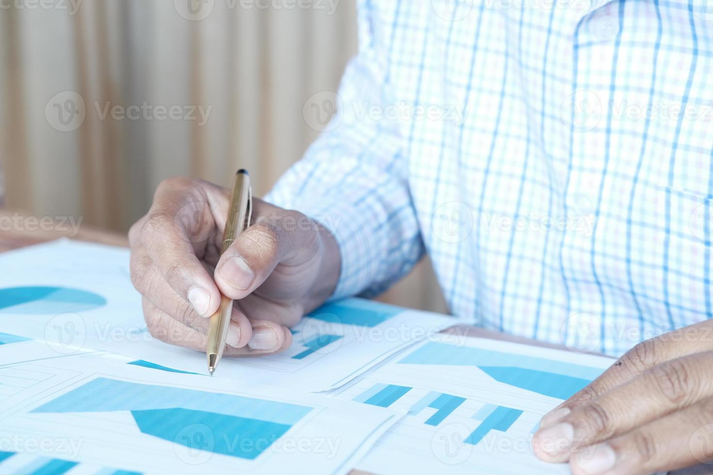 mans hand som håller en penna som analyserar finansiella data och diagram foto