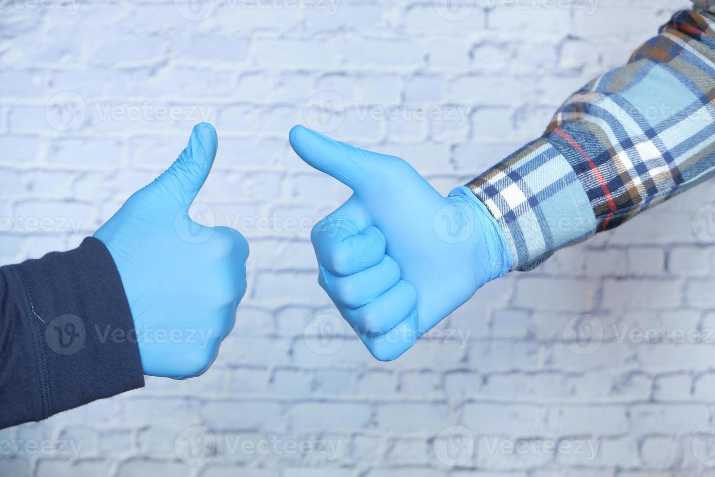 närbild av två personer som bär medicinska handskar som visar ett tummen upp tecken foto