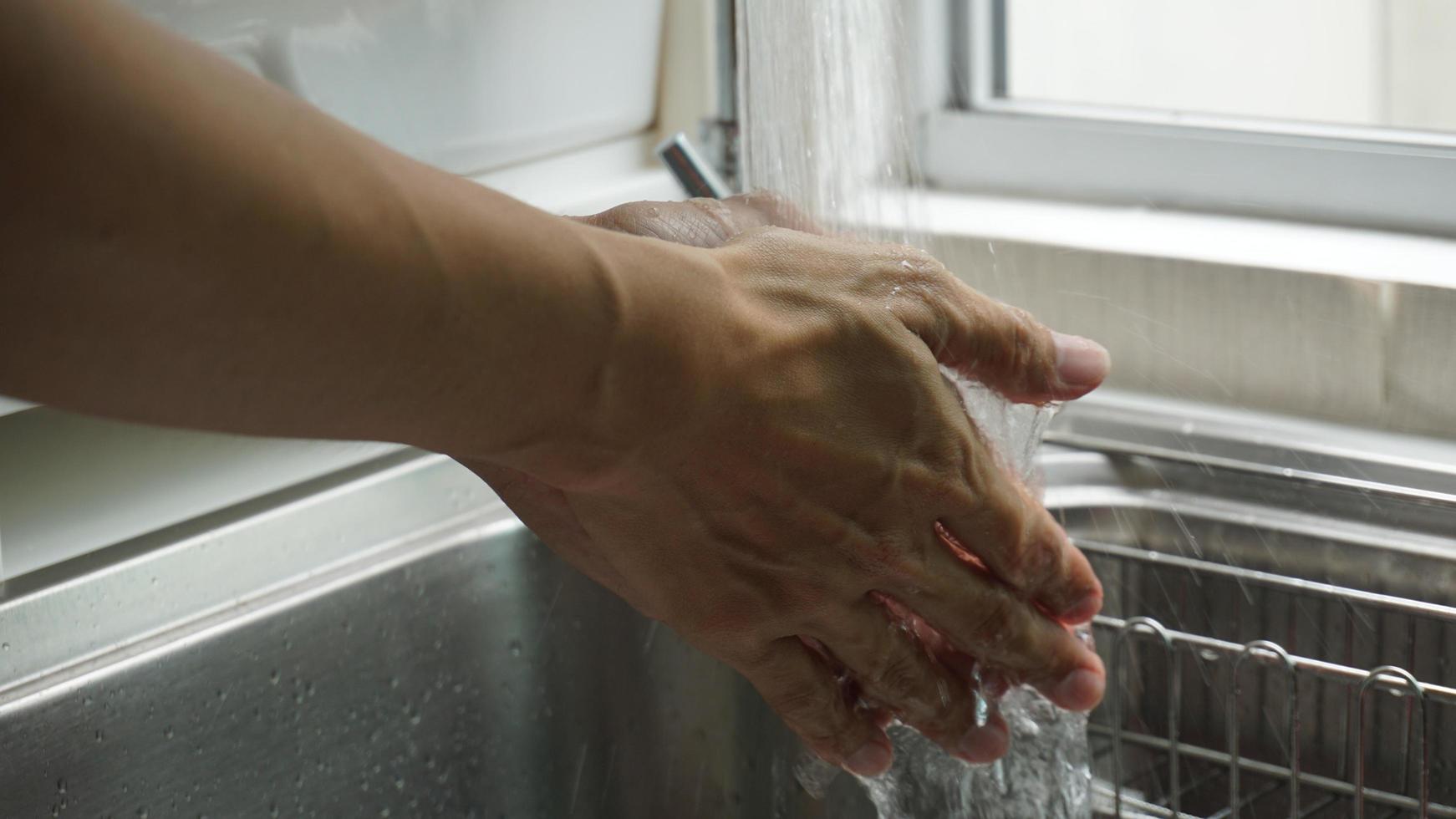 två händer tvättas i ett handfat vid ett fönster foto