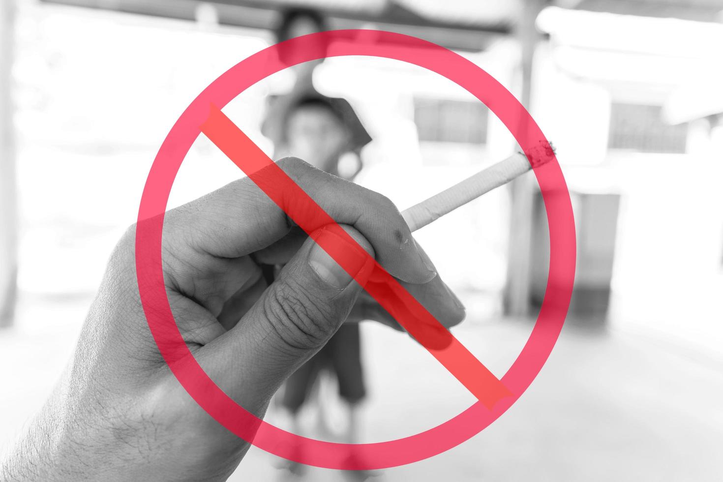 allmänt förbud tecken överlagrad på handen håller cigarett med suddiga barn i bakgrunden foto