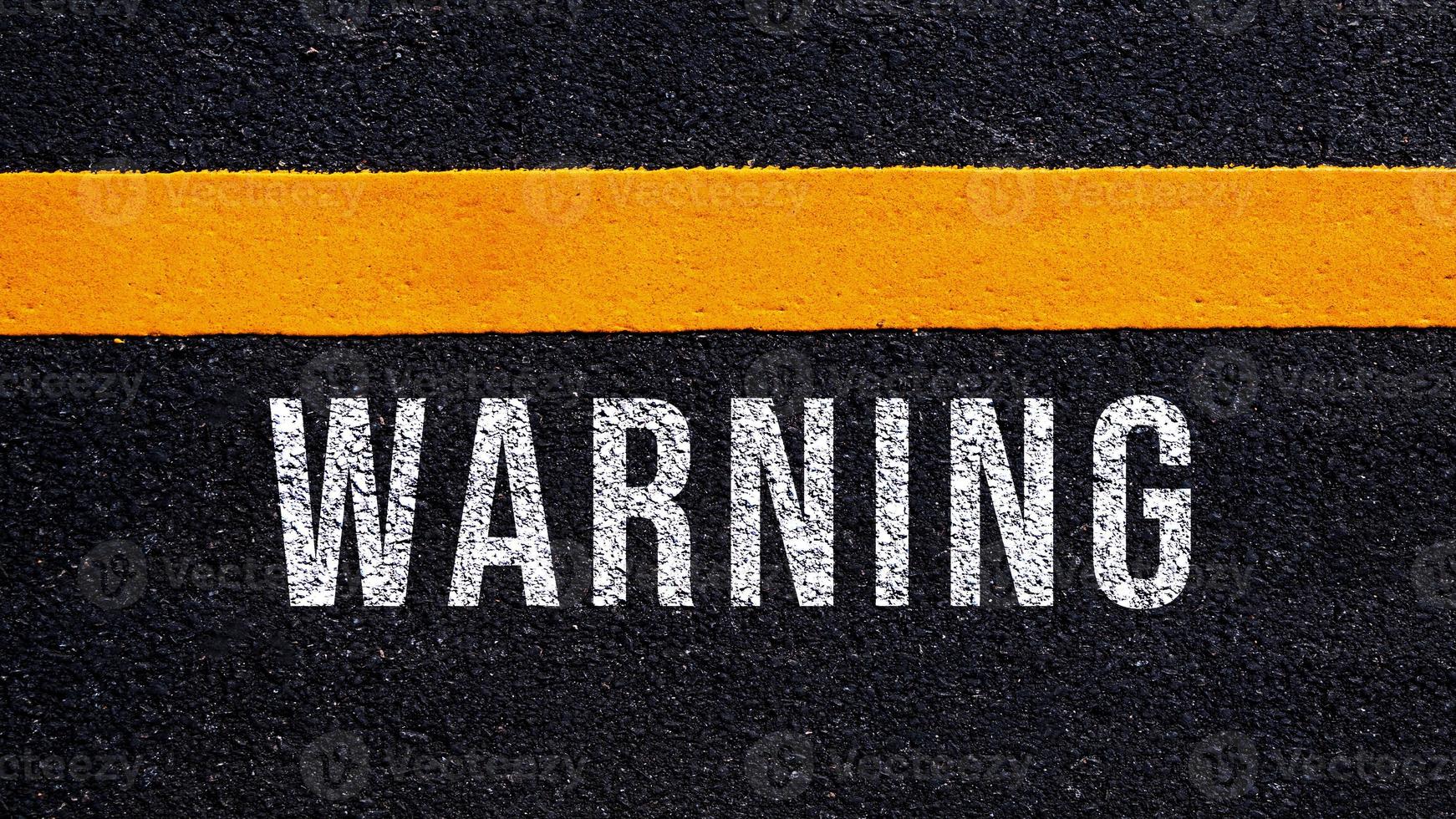 varning skriven och gul linje på de väg i mitten av de asfalt väg, varning ord på gata. foto