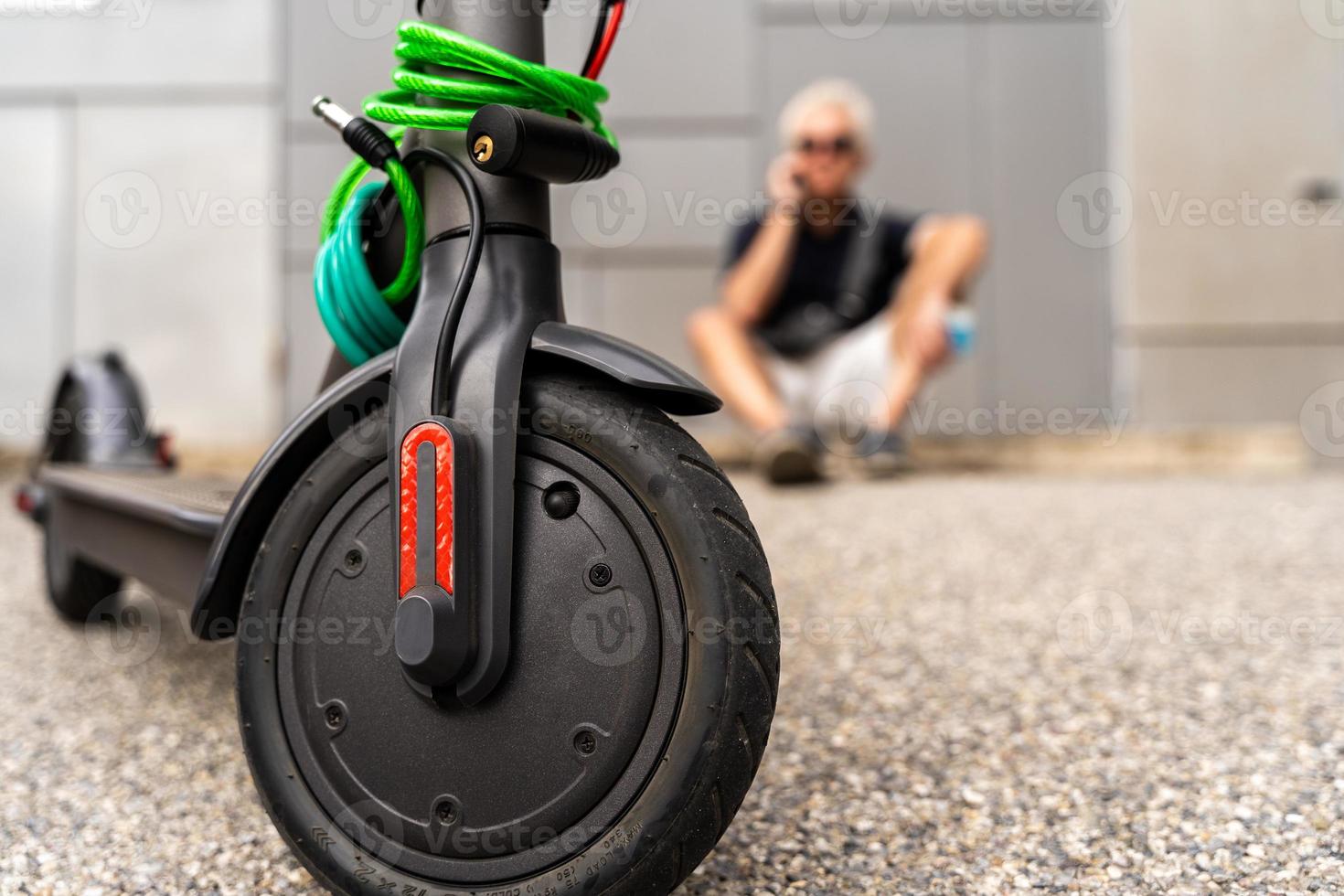 pendlare hipster man med elektrisk skoter är använder sig av smartphone i de förorter foto