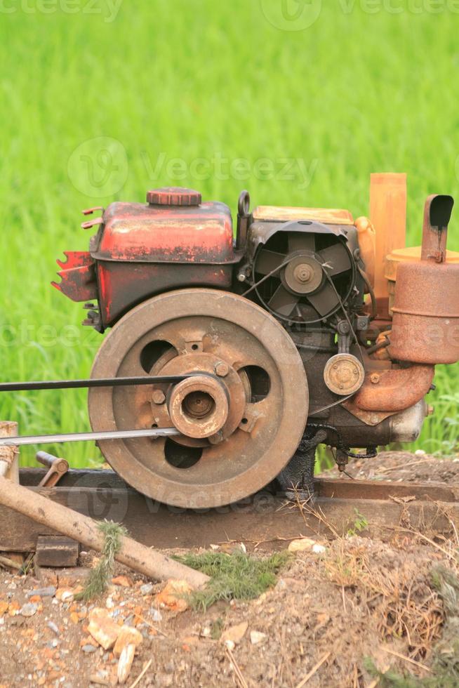 de gammal röd vatten pump den där är spinning på full kraft till pump vatten in i de ris fält av jordbrukare under de ris växande säsong i lantlig thailand. foto