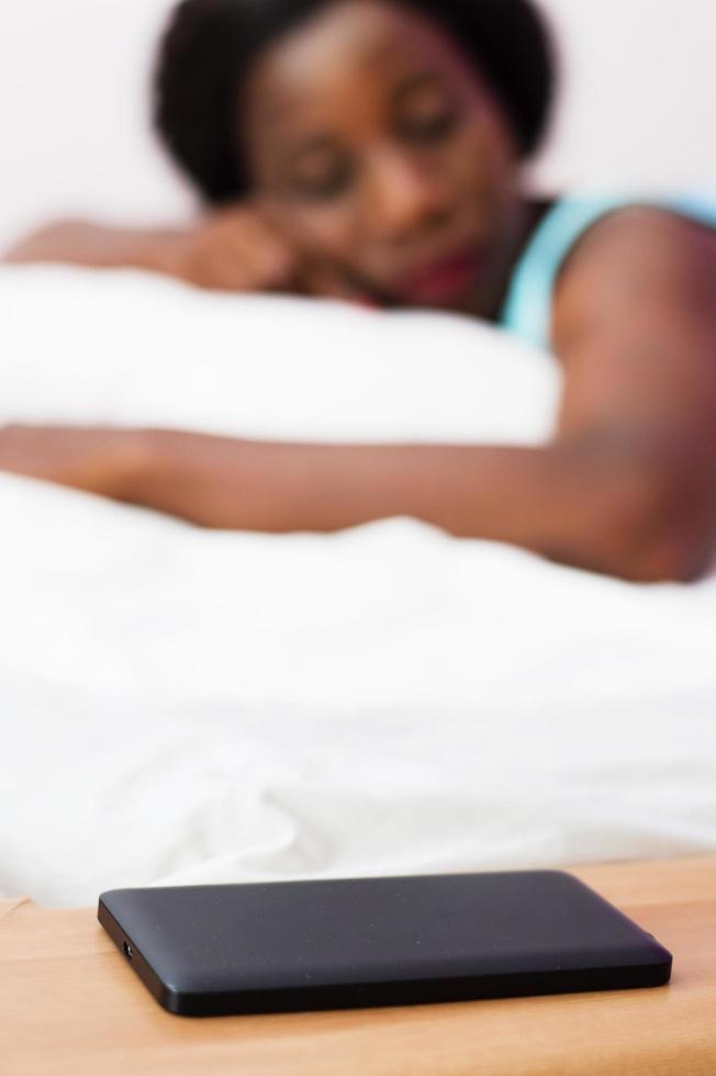 kvinna som sover med sin mobiltelefon bredvid henne foto