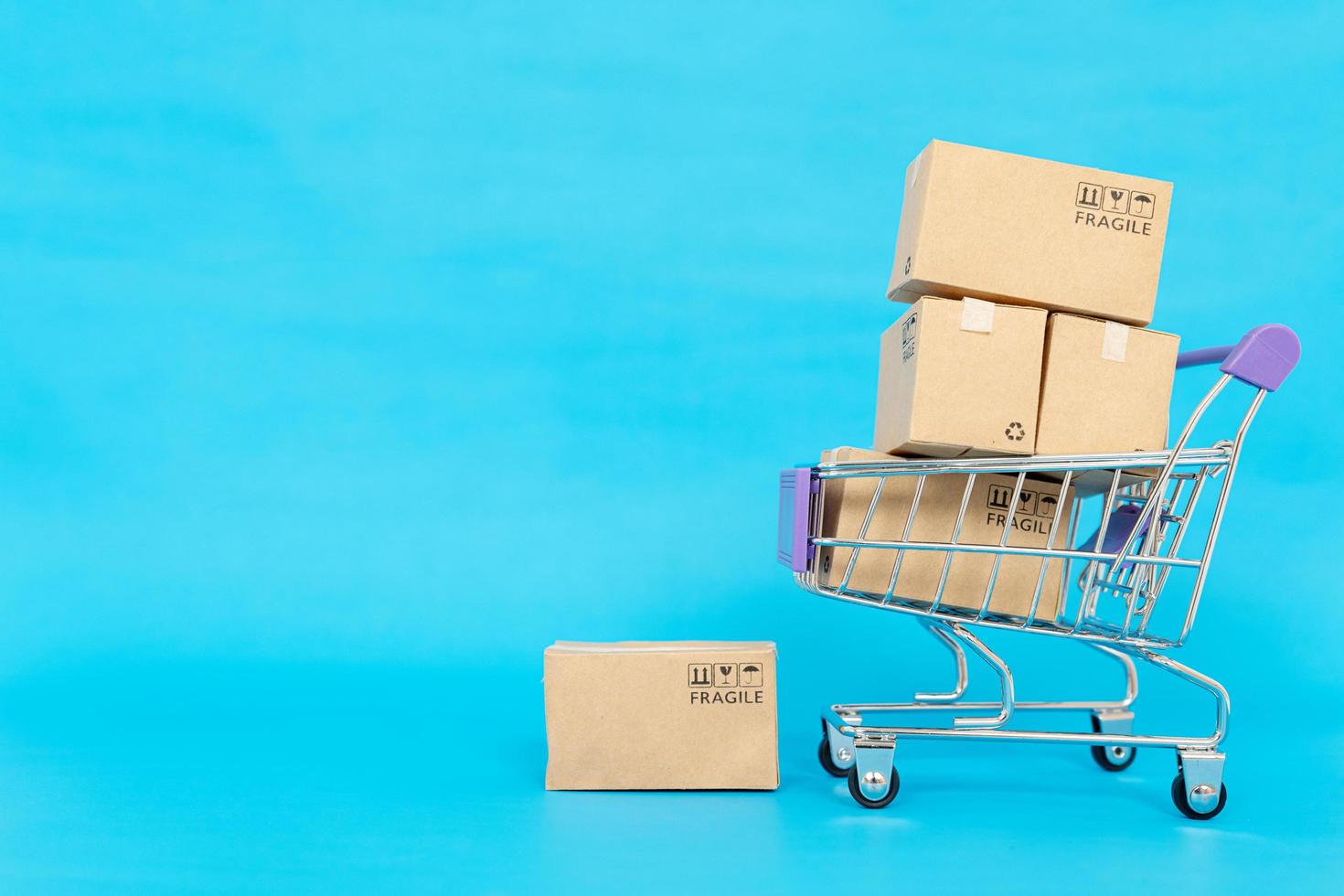 papperslådor i en vagn på en blå bakgrund. online shopping eller e-handel koncept och leverans servicekoncept med kopia utrymme för din design foto