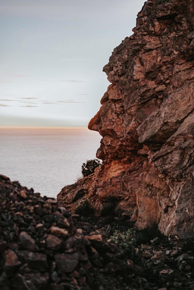 brun klippformation nära vattenkroppen under dagtid foto