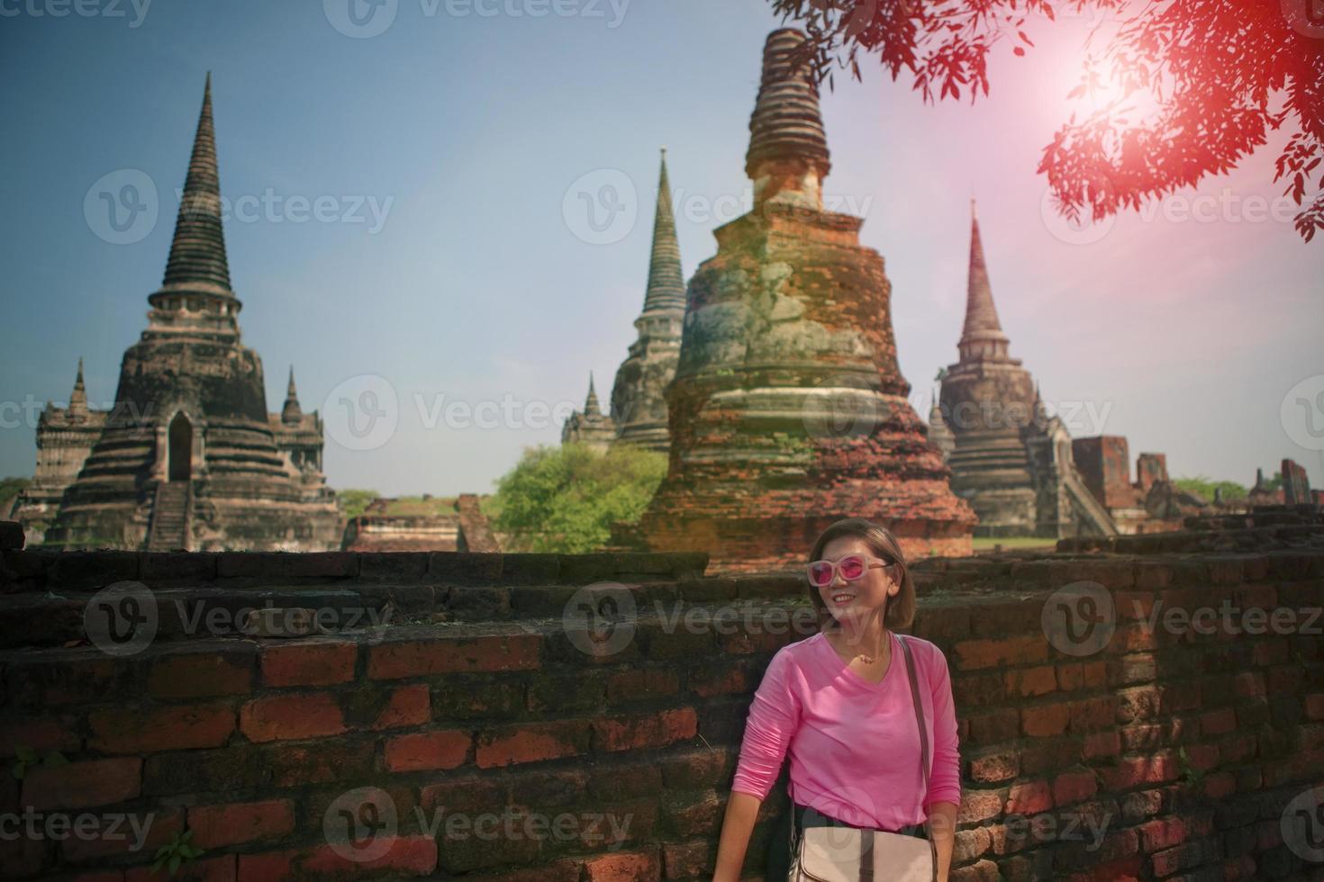 skön kvinna stående mot gammal tegel vägg med asiatisk tempel bakgrund foto