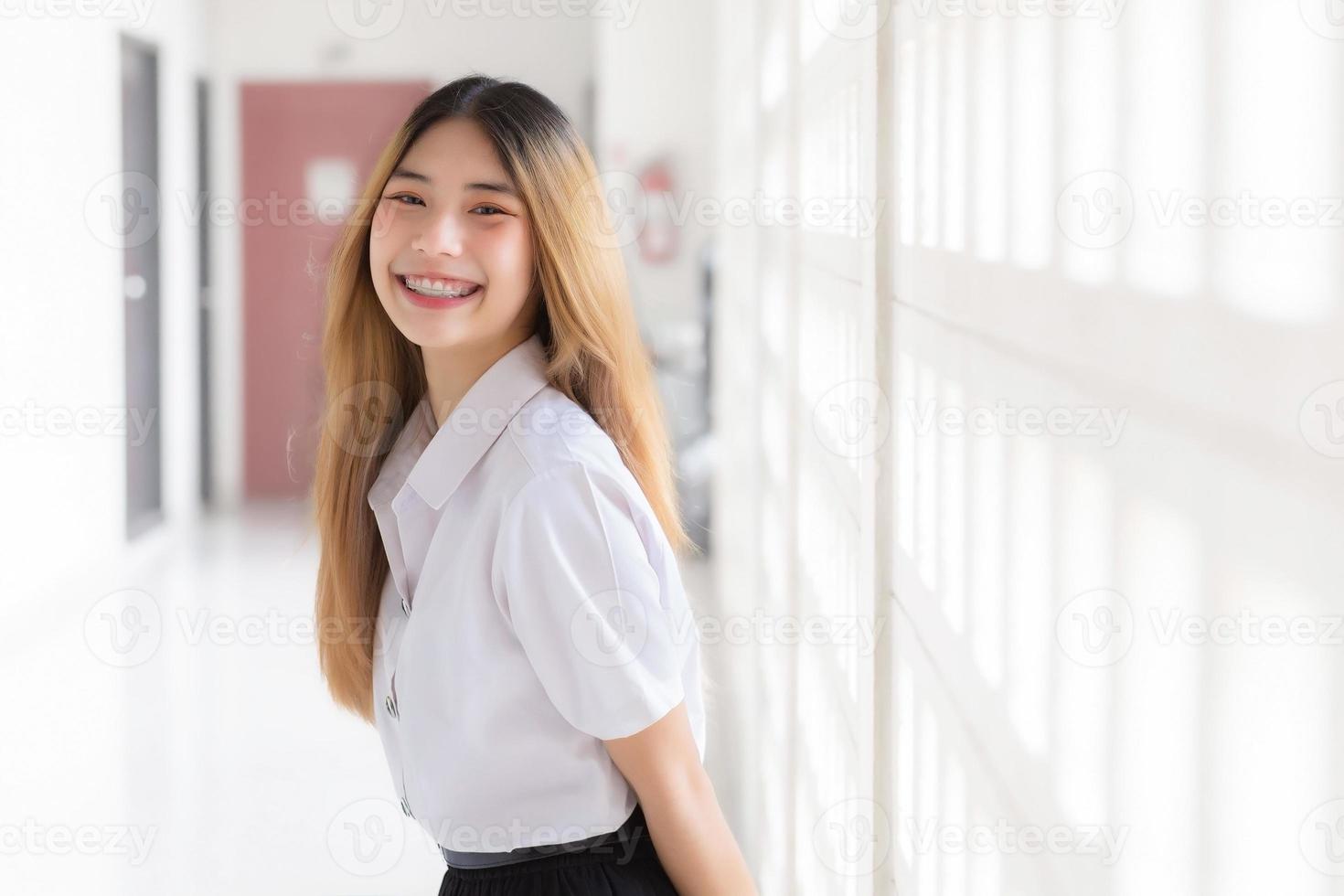 porträtt av söt thai studerande i universitet studerande enhetlig. ung asiatisk skön flicka stående leende självsäkert på universitet. foto