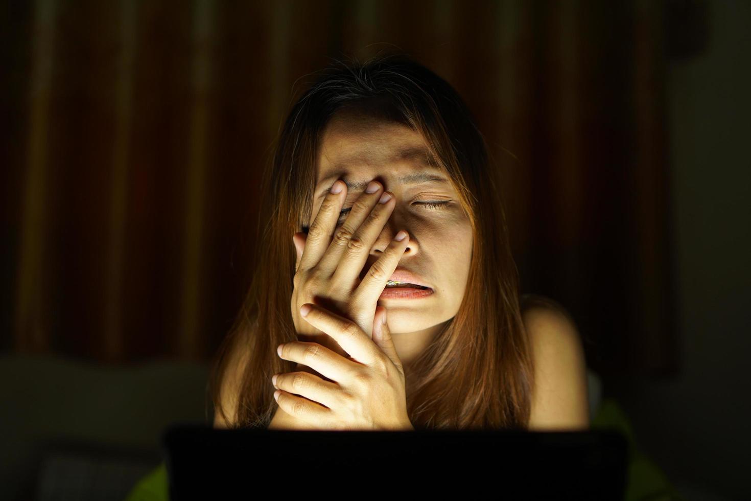 asiatisk kvinnor lida från ansträngda ögon från ser på datorer i låg ljus. Kolla på bio uppkopplad foto